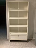 Front view of the bookcase showing 4 shelves and bottom drawer closed.