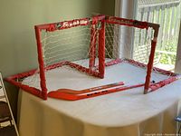 Two red plastic framed mini hockey nets with white nets and Franklin NHL branded trim, placed side by side indoors.