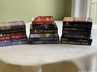 Two stacks of novels displayed on a table with titles and authors visible, showing condition and variety.