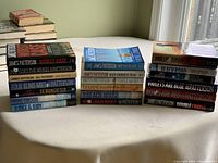 Set of 19 James Patterson novels displayed on a table in three stacks, showing spines and part of cover artwork.