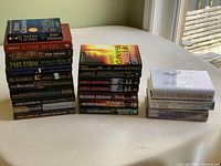 Overview of the 21 novels showing three stacks of books on a table near a window, displaying various titles and authors.