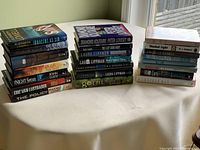 Photo shows three stacks of novels with visible titles and authors, providing a clear view of 22 novels in total in very good condition.