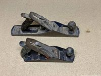 Top view of two wood hand planers placed side-by-side showing the handles and knobs