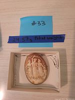 Cameo pin in box with handwritten #33 and weight note