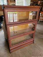 Front view showing three stacking sections with glass-front doors and wooden frame.