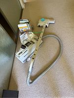 Full view of Electrolux vacuum cleaner with hose, floor head, power cord, and vacuum bags and filters in background.