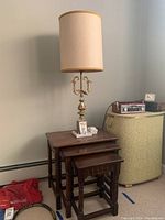 Full view of lamp atop three nested wooden tables with dark stain and turned legs in a room setting