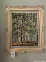 Framed painting hung on a wall showing entire artwork and decorative frame