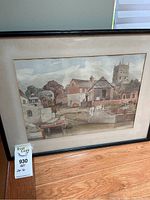 Full view of framed watercolour painting showing village and church tower scene with mat and simple dark wooden frame.