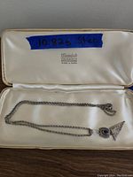 Full view of the necklace inside box showing chain and pendant, along with handwritten label indicating 10.82g sterling silver.