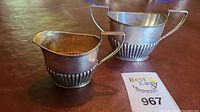 Overview of creamer and sugar bowl set on table with lot tag