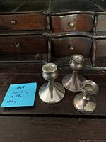 Front view of three sterling silver candlestick holders with weight note