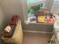 View of various vintage items arranged near a window ledge including clocks, radio, books, and a hamper.