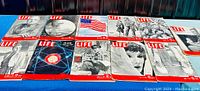 Ten large format LIFE magazines from the 1940s arranged in two rows, showing a variety of covers with period photography, American flag image, and atomic-related imagery.