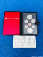 Open leather folio showing red interior and six Canadian proof coins in plastic holders plus specification paper beneath