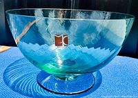Photograph showing side view of the clear aqua Murano art glass bowl with visible Carlo Moretti label on the exterior.