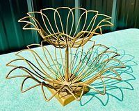 Side view of the two-tier metal wire fruit bowl showing the flower petal design and sturdy square base.