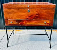 Front view showing vintage pine wooden box on iron base with drawer and keyhole.
