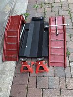 Overview of two red metal ramps, black creeper, two red Pro Series jack stands, and a silver cross wrench