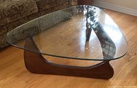 Full view of triangular glass top coffee table on hardwood floor
