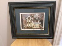 Full view of the Halloween themed picture in a black and gold wooden frame under glass hanging on the wall.