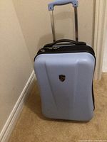 Front view of light blue hard shell Heys carry-on luggage with telescoping handle extended.