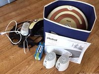 Photo showing the robotic vacuum, docking station, battery pack, instruction manuals, and two virtual wall devices in a box.