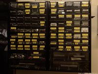 Two metal parts cabinets with plastic drawers labeled mostly with hardware types and sizes containing screws, washers, anchors, bolts