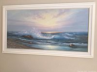 Frontal view of full ocean framed picture showing waves and rocks with a soft sunrise or sunset sky.