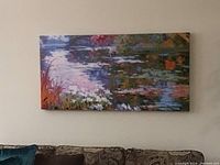 Full view of the Monet inspired river scene canvas art hanging above a patterned couch, showing the overall composition and frame.