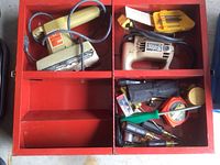 Overview of toolbox interior showing electric sander, jigsaw, and hand tools organized in compartments