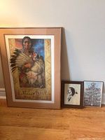 Full view of the three pictures: large Sitting Bull poster, small framed drawing, and small tree of life poster on the floor against wall