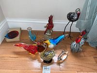 Photo showing all eight art glass birds and two colored glass ornaments on floor against wall.