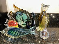 Group photo of six art glass figurines including fish, swans, cat in various colors.