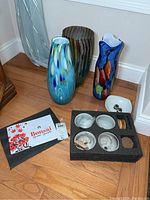 Full view of the three art glass vases displayed on floor alongside bonsai grow kit components including small containers and planting materials in foam insert.