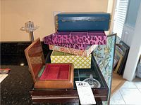 Various vintage jewelry boxes and organizers stacked, showing wood, fabric patterns, and blue box