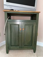 Front view of green Ethan Allen media cabinet showing open shelf and two paneled doors with wooden knobs.