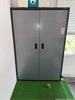 Front view of Gladiator metal utility cabinet with double doors, gray diamond plate texture, black frame, and lockable handles.