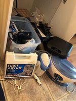 Photo showing the full lot with First Aid Kit, Waterpik flosser, heating pad, plastic bin, and other items on the floor.