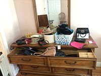 Wide shot of all purses and hats arranged on a wooden dresser with mirror