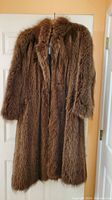 Full view of long brown racoon fur coat hanging
