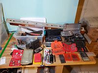 Overall view of table with laid out hand tools, bit sets, socket sets, and level showing quantity and variety of items