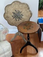 Full view of both vintage accent tables side-by-side showing the flip-top beige table with floral design and the smaller dark wood tripod table.