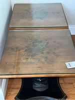 Top view showing two matching wooden side tables with painted floral designs under glass tops.
