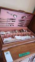 Opened wooden canteen showing pink velour interior with Community Plate cutlery arranged inside.