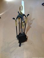 Complete four-piece fireplace tool set with brass handles and cast iron shafts including shovel, poker, broom, and stand.