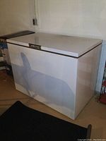 Front view of white Beaumark chest freezer with control panel on lid edge and minor dirt marks at base.