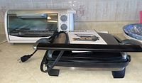 Photo shows Black & Decker Classic Line Toast-R-Oven and Cuisinart Griddler Express with manual displayed on countertop.