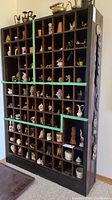 Front view of large wooden shelf with many small compartments filled with miniature figurines and knick knacks