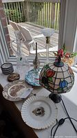 Wide view showing lamp, plates, decanter, and coasters arranged on window sill with outdoor deck visible through window.